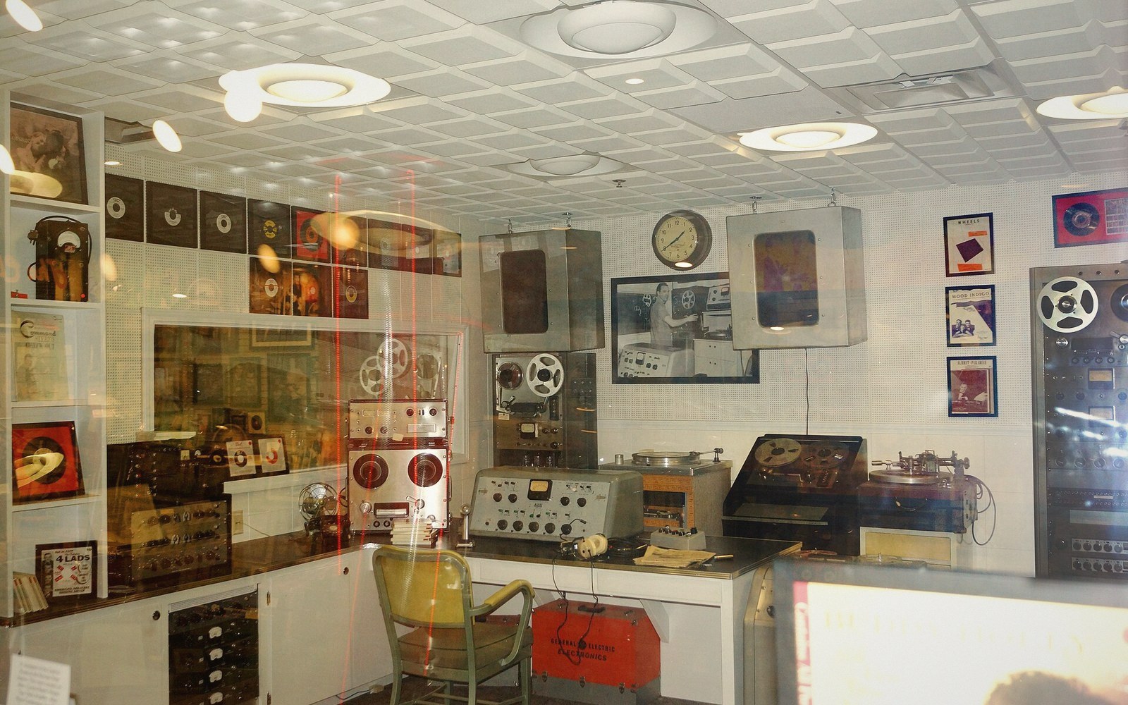 Vintage recording studio display with reel-to-reel tape machines, speakers and old records on shelves