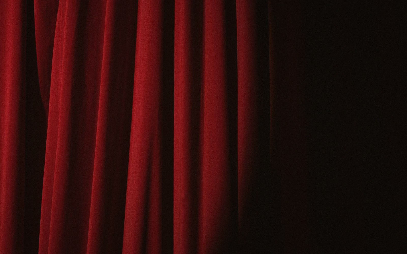 The heavy velvet house curtain seen from the wings, folds catching side light